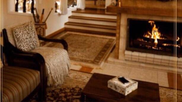 A cozy living room with a fireplace, a sofa, and a coffee table. - Pousada Mar Deny Campos (Campos do Jordão)