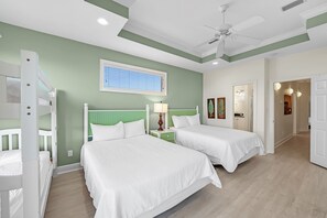 A bedroom with two beds, a ceiling fan, and a window with blinds. - Sea Monster, East. Pool. Extra fridges. Lots of space. And right on the beach! (Gulf Shores)