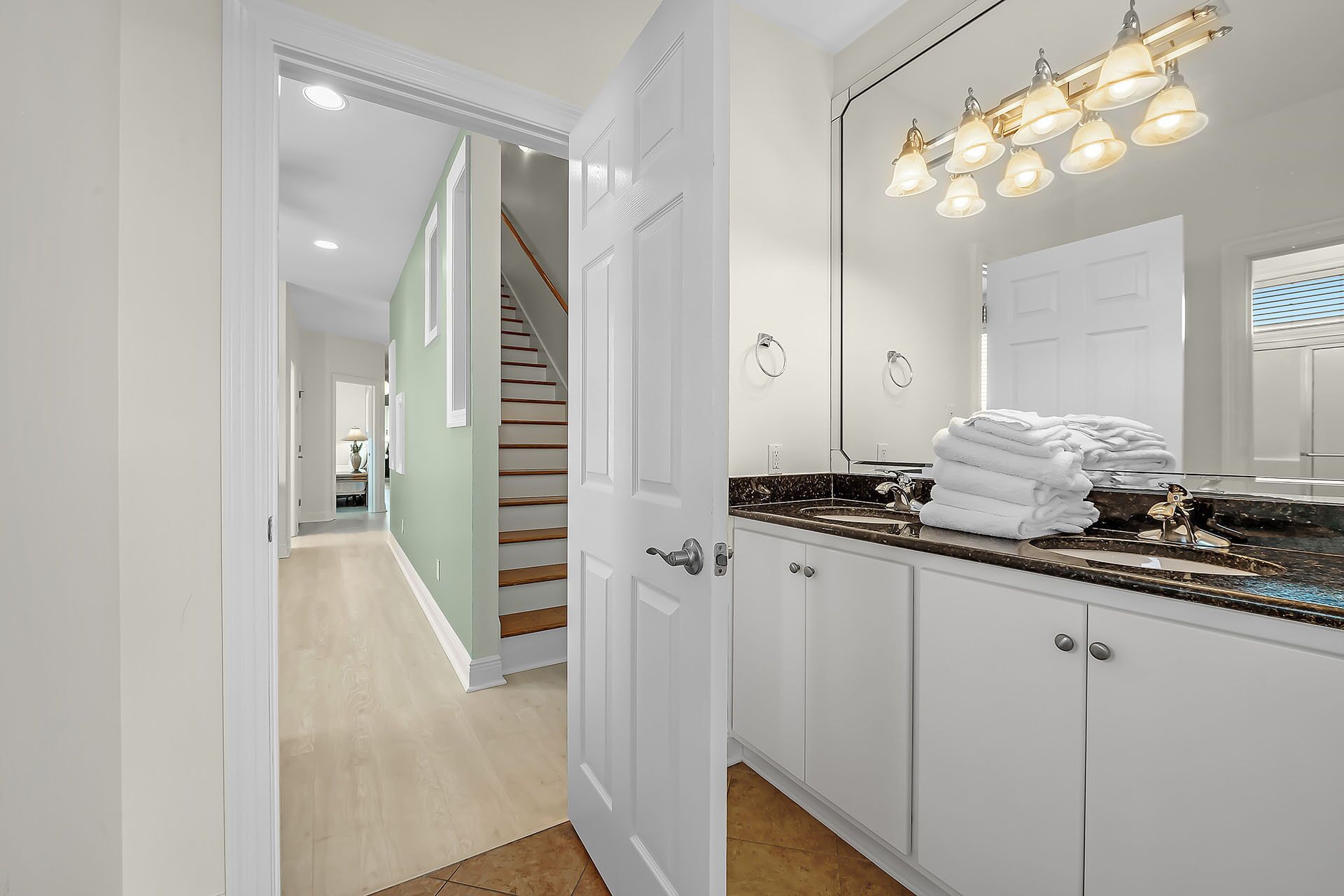 A modern bathroom with a large mirror, white cabinets, and a marble countertop.
