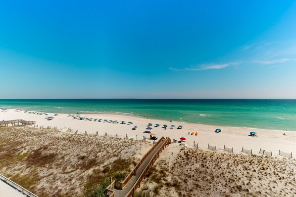 Walk along the boardwalk to the sandy beach, where umbrellas and beach chairs line the shore.