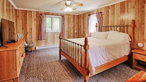 A bedroom with a wooden bed, a desk, and a chair.