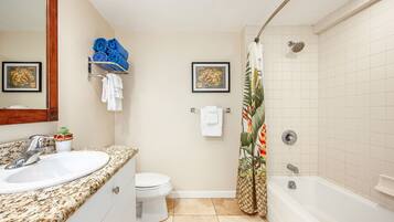 Une salle de bain avec un lavabo, des toilettes et une baignoire. On y trouve des serviettes et un rideau de douche.