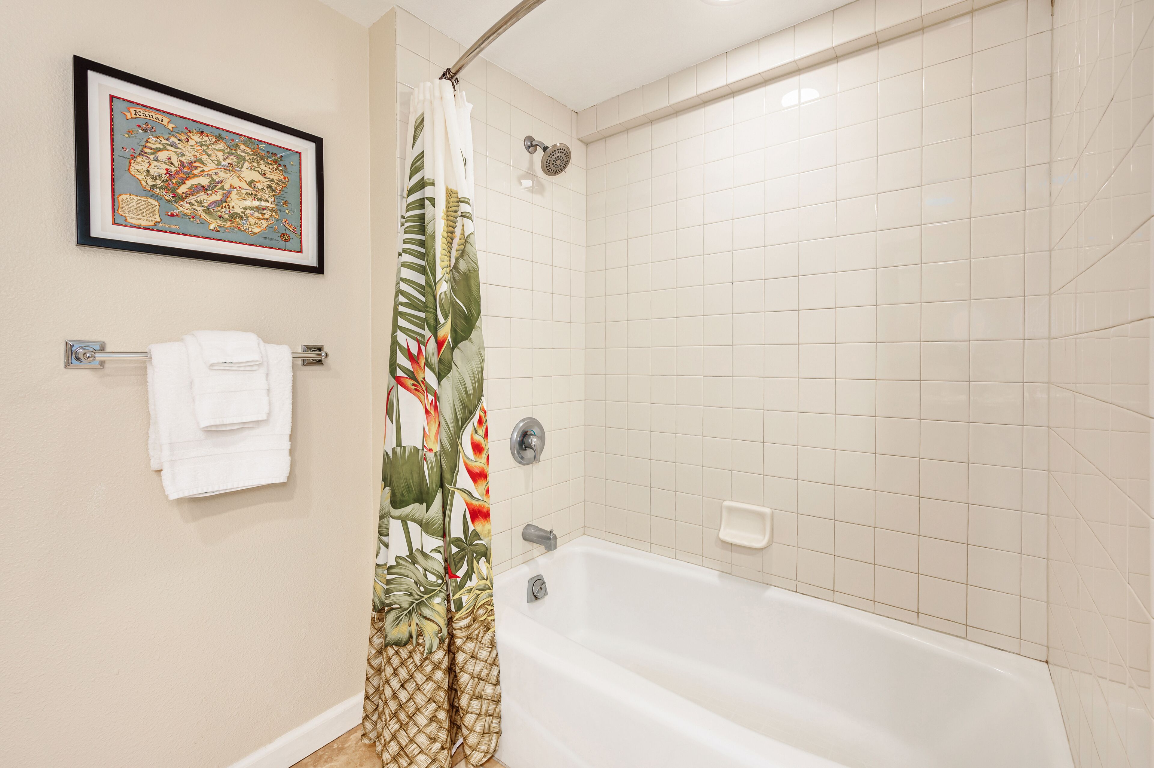 A bathroom with a bathtub, a shower, a framed map on the wall, and a towel rack with a folded towel.