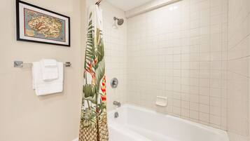 A bathroom with a bathtub, a shower, a framed map on the wall, and a towel rack with a folded towel.