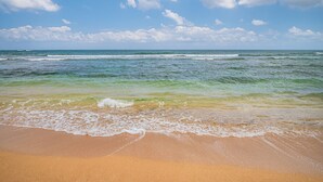 Een strand met golven die zachtjes op het strand komen en een heldere lucht.