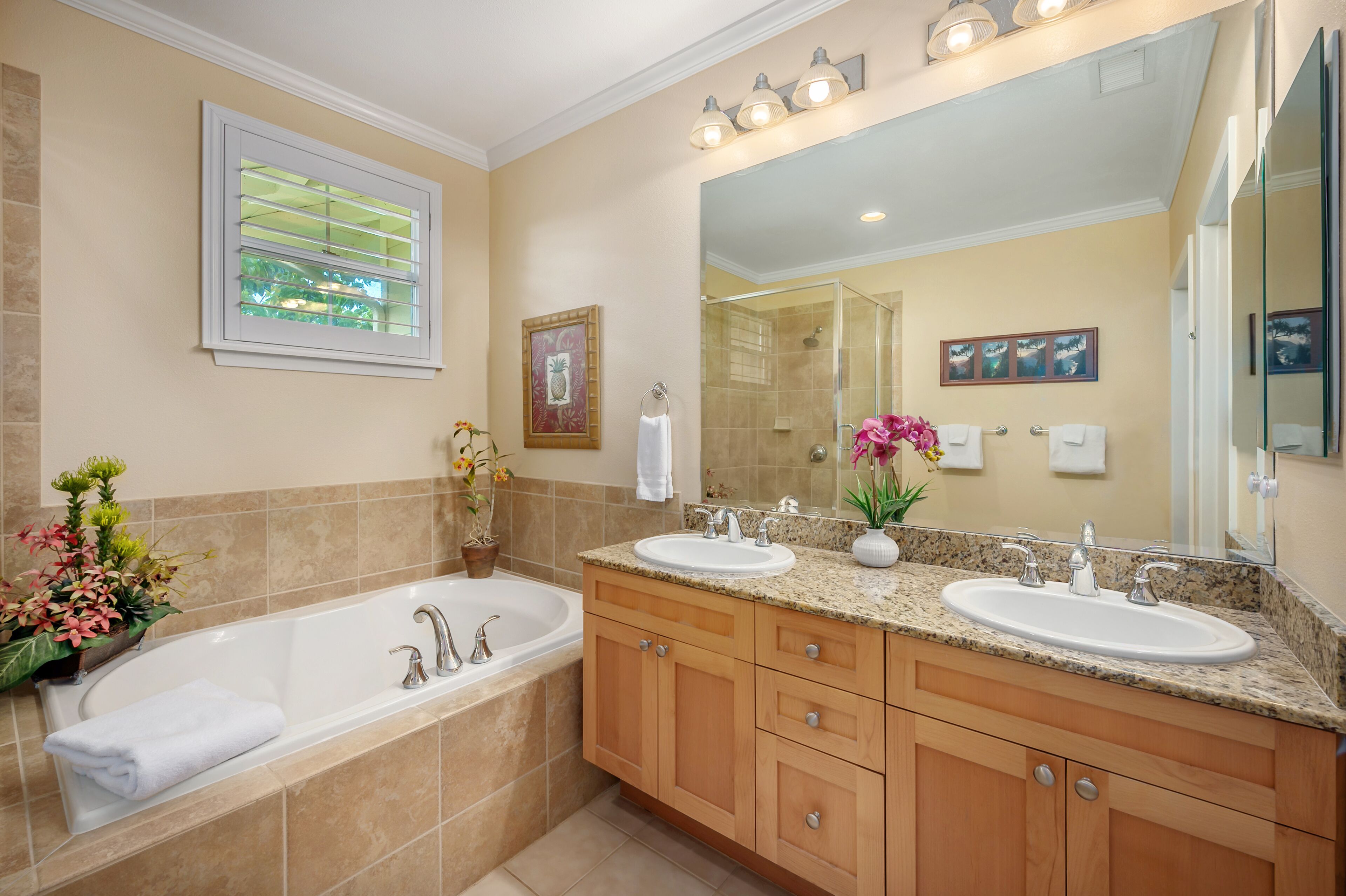 Une salle de bain avec une grande baignoire, deux lavabos, des meubles en bois et un grand miroir.