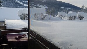 Una habitación con vistas a un paisaje nevado, una cama y una mesa con sillas.