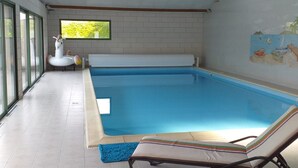 An indoor swimming pool with a tiled floor, a lounge chair, and a mural on the wall. - Gite le Clos Ferré SWIMMING POOL TENNIS (Brézé)