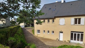 A two-story building with a beige facade, multiple windows, and a garage door. - Gite le Clos Ferré SWIMMING POOL TENNIS (Brézé)