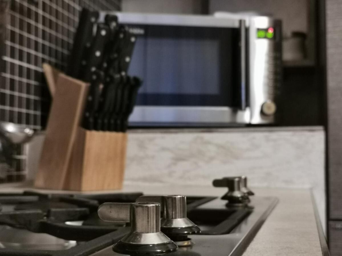 A kitchen with a gas stove, a microwave, and a knife block.
