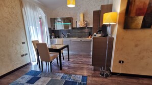 Una sala de estar moderna con comedor, una cocina al fondo y un amplio ventanal con cortinas.