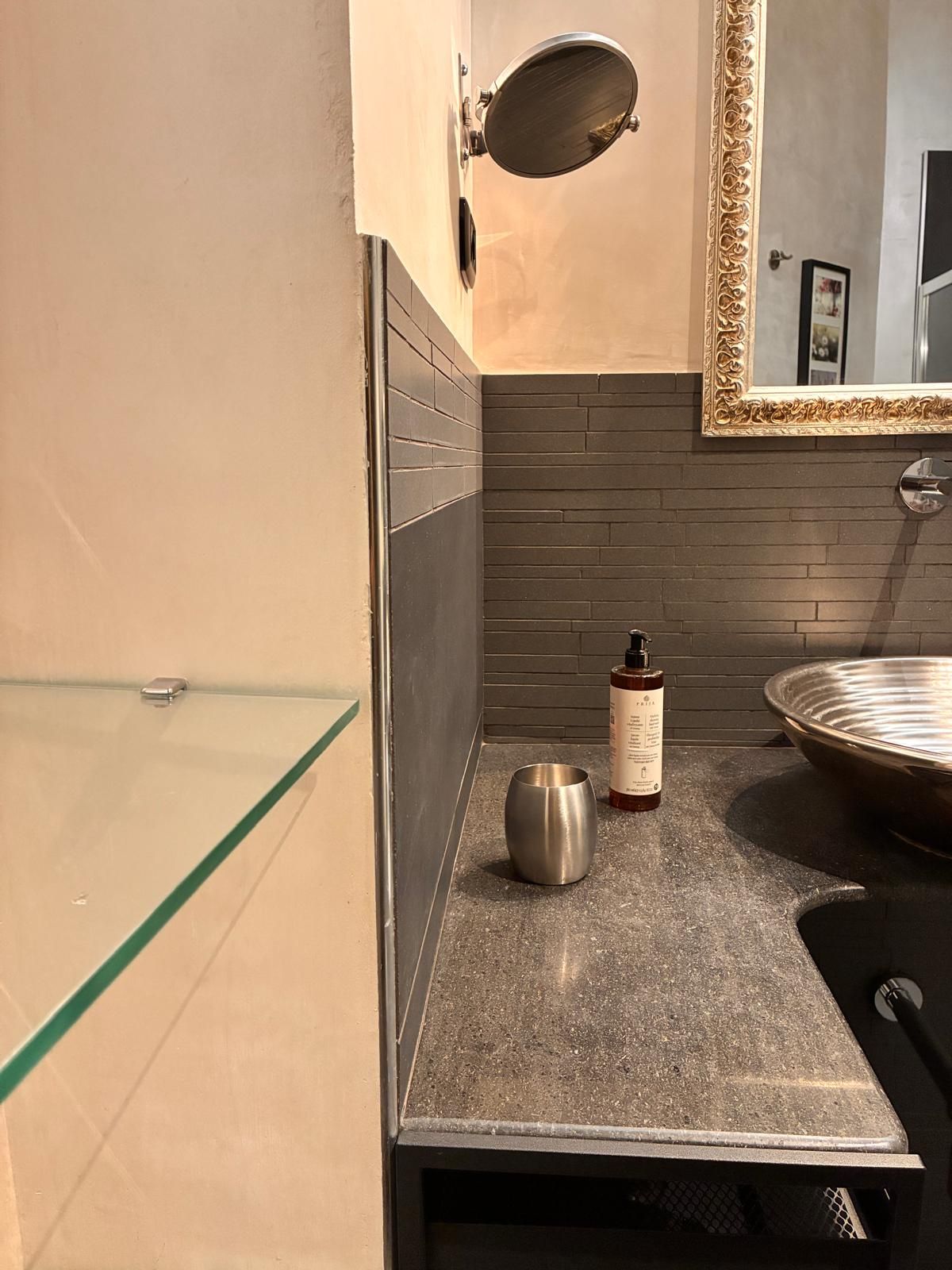 A bathroom with a glass shower enclosure, a sink with a round basin, and a mirror with an ornate frame.
