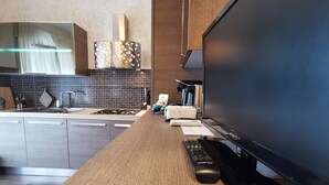 Una cocina moderna con encimera de madera, horno empotrado y un televisor de pantalla plana grande.