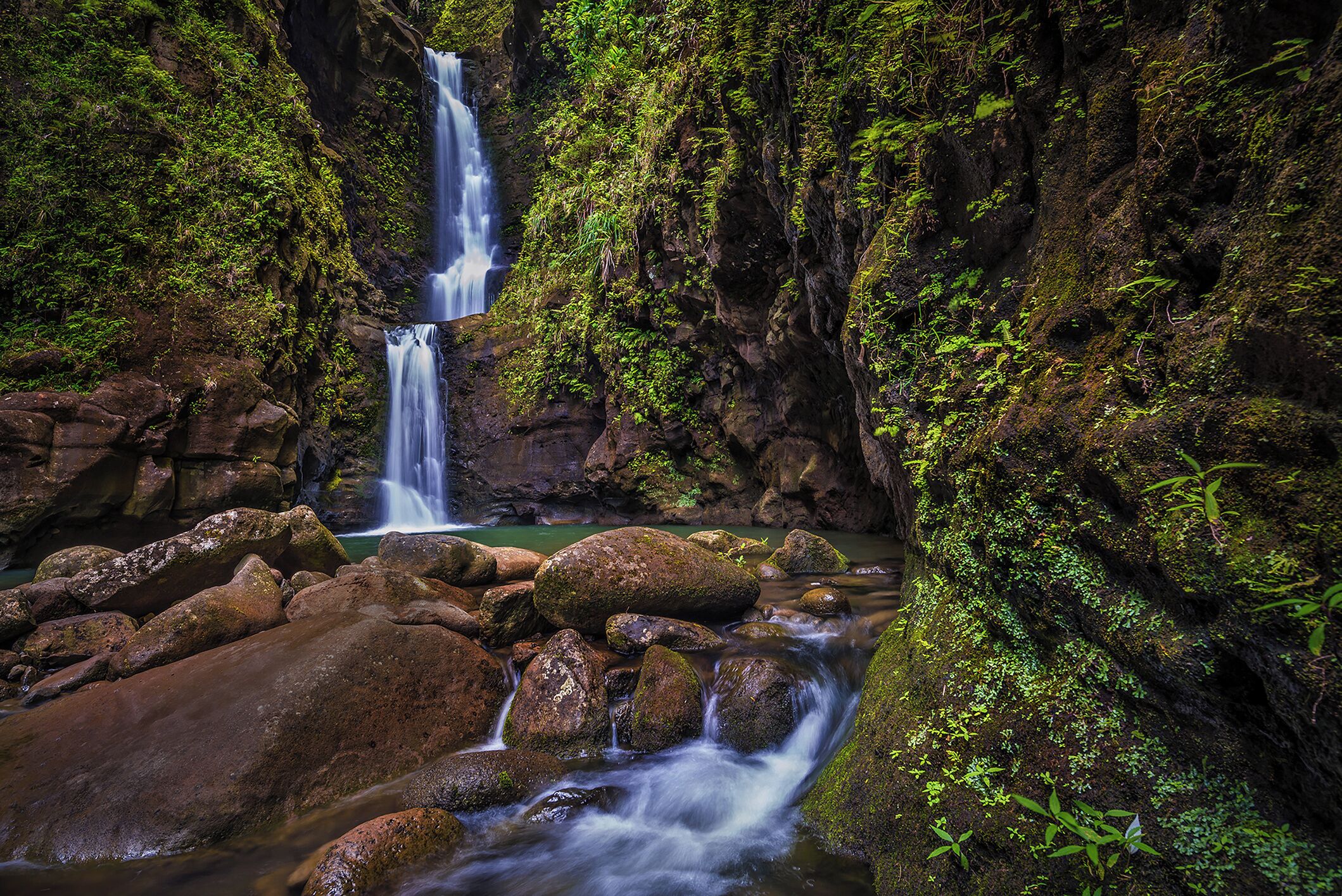 Una cascada natural rodeada de rocas y follaje.