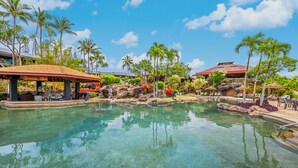 A clear pool with a bar area, palm trees, and a building with a red roof. - HBR Couples Lockoff 7201, Ocean View, Quiet Location,  Add'l Resort Fees (Princeville)