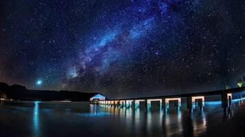 Un muelle se adentra en una masa de agua bajo un cielo estrellado.