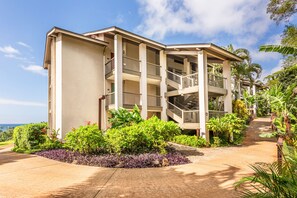 A multi-story hotel with a central courtyard, balconies, and tropical landscaping. - HBR Family Condo 7201/2, Ocean View, Quiet Location, W/D,  Add'l Resort Fees (Princeville)