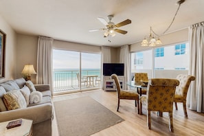 Enjoy ocean views from the large window in this living room, featuring a flat-screen TV, dining table, and comfortable sofa.