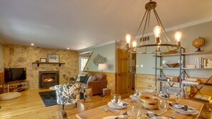 Una sala de estar acogedora con chimenea, un comedor listo para una comida y un televisor en una esquina.
