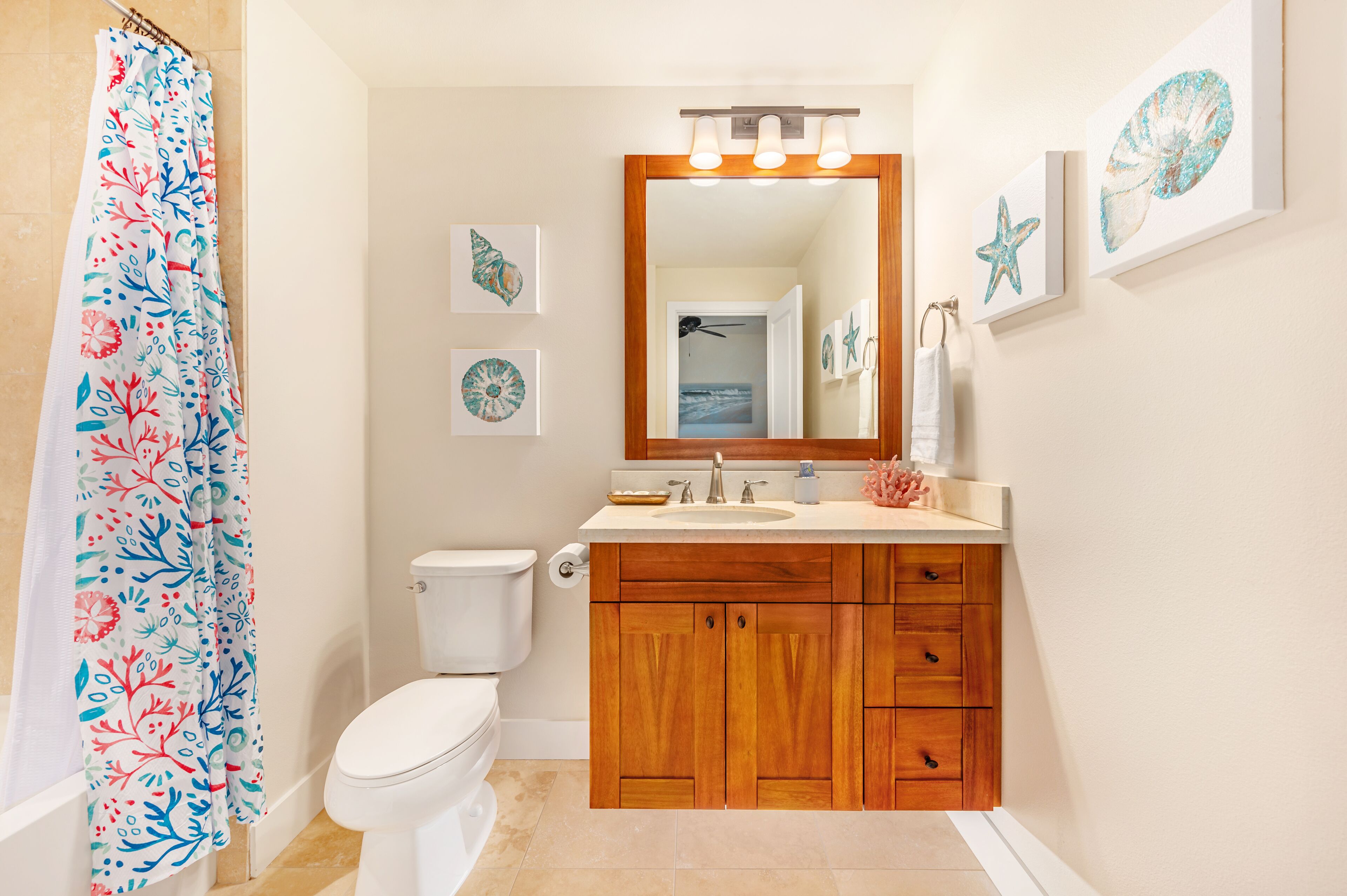 Un baño con cortina de ducha, inodoro, lavabo, espejo y armarios de madera.