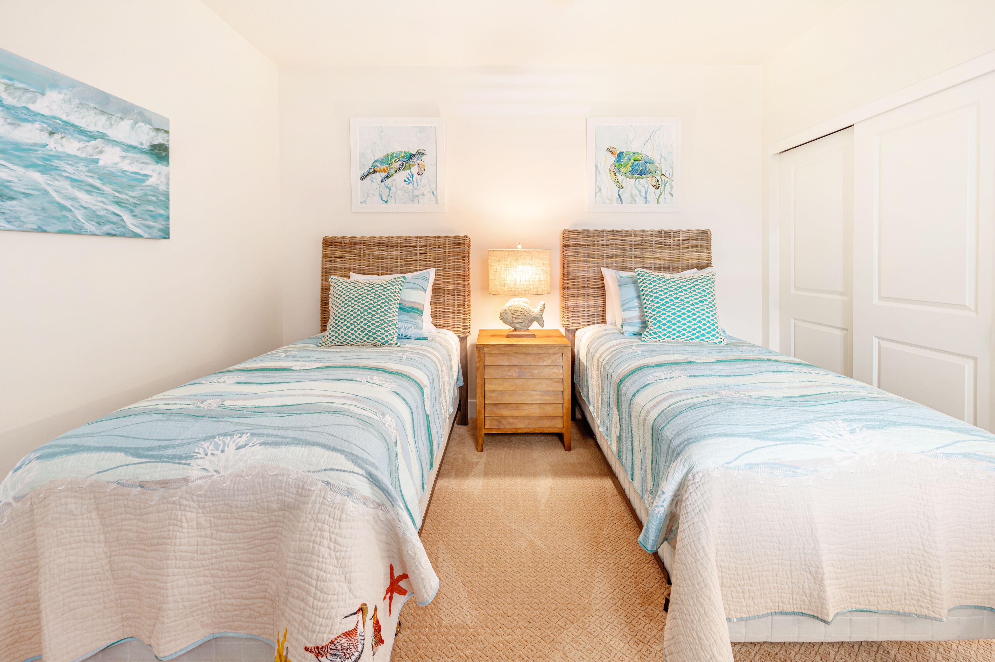 Una habitación con dos camas individuales, una mesita de noche con lámpara y decoración mural con aves.