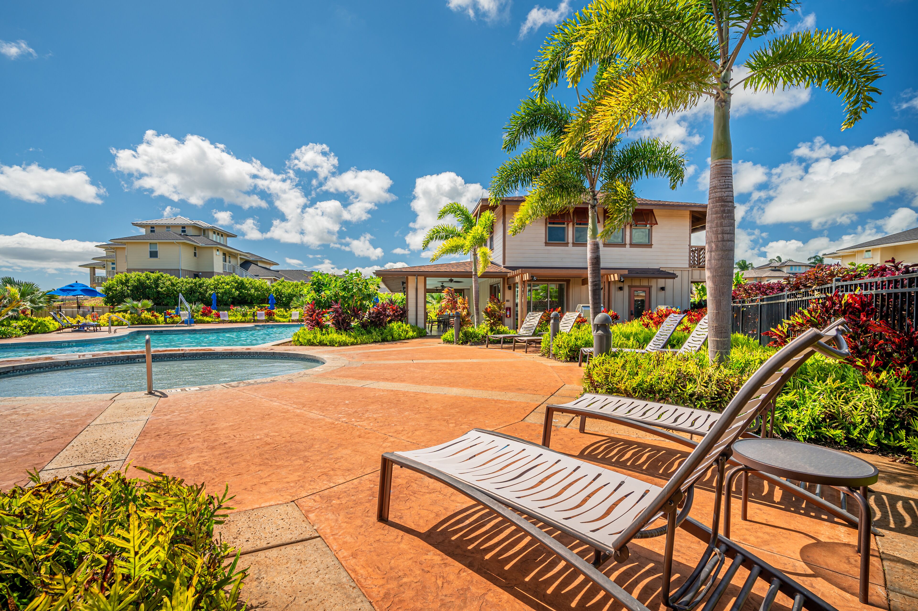 A pool area with lounge chairs, a swimming pool, and a building with a balcony.