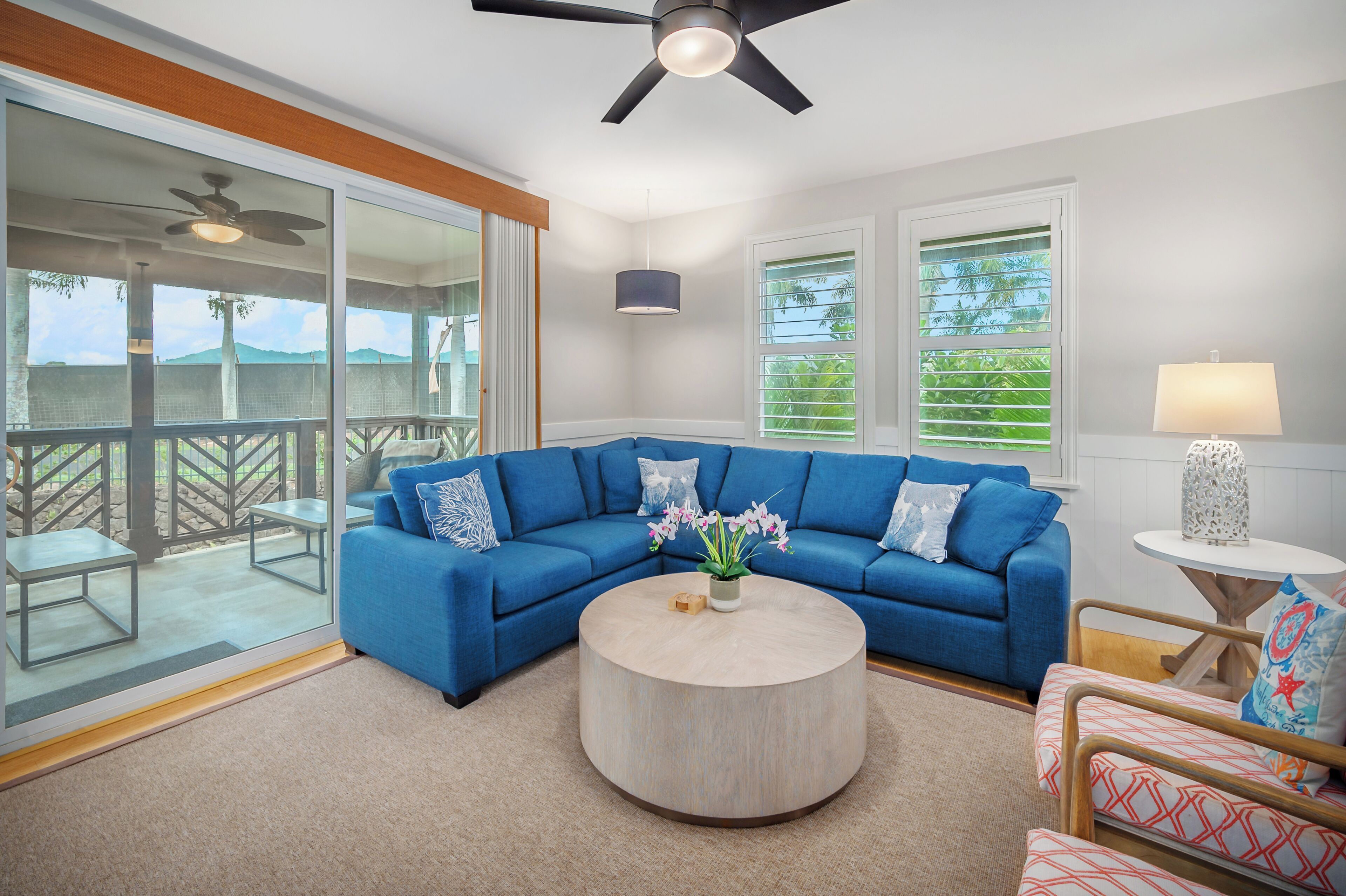 A modern living room with a blue sectional sofa, a round coffee table, and a ceiling fan.
