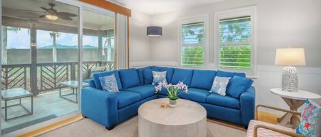 A modern living room with a blue sectional sofa, a round coffee table, and a ceiling fan.