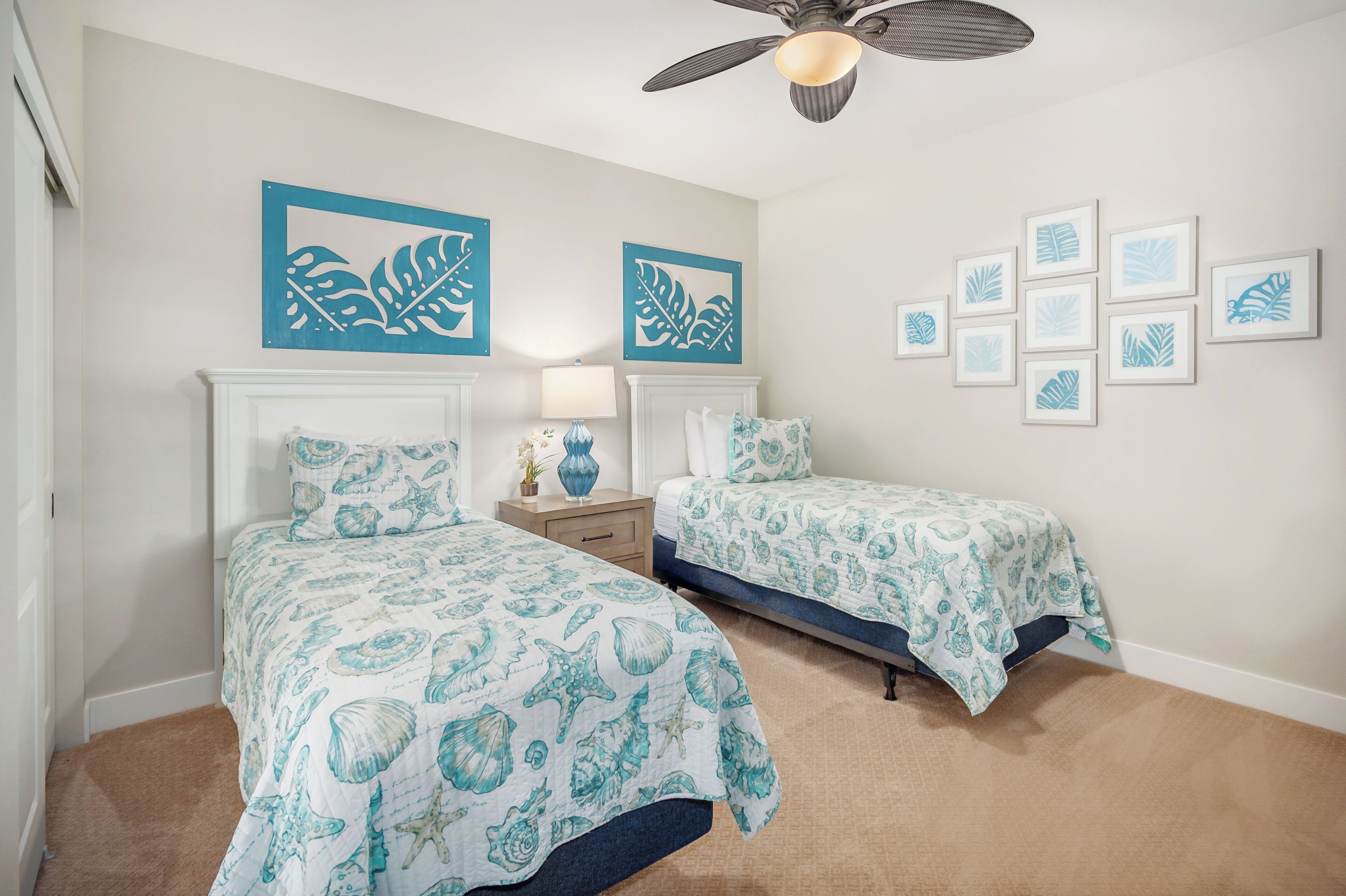 A bedroom with two beds, a ceiling fan, and wall art.