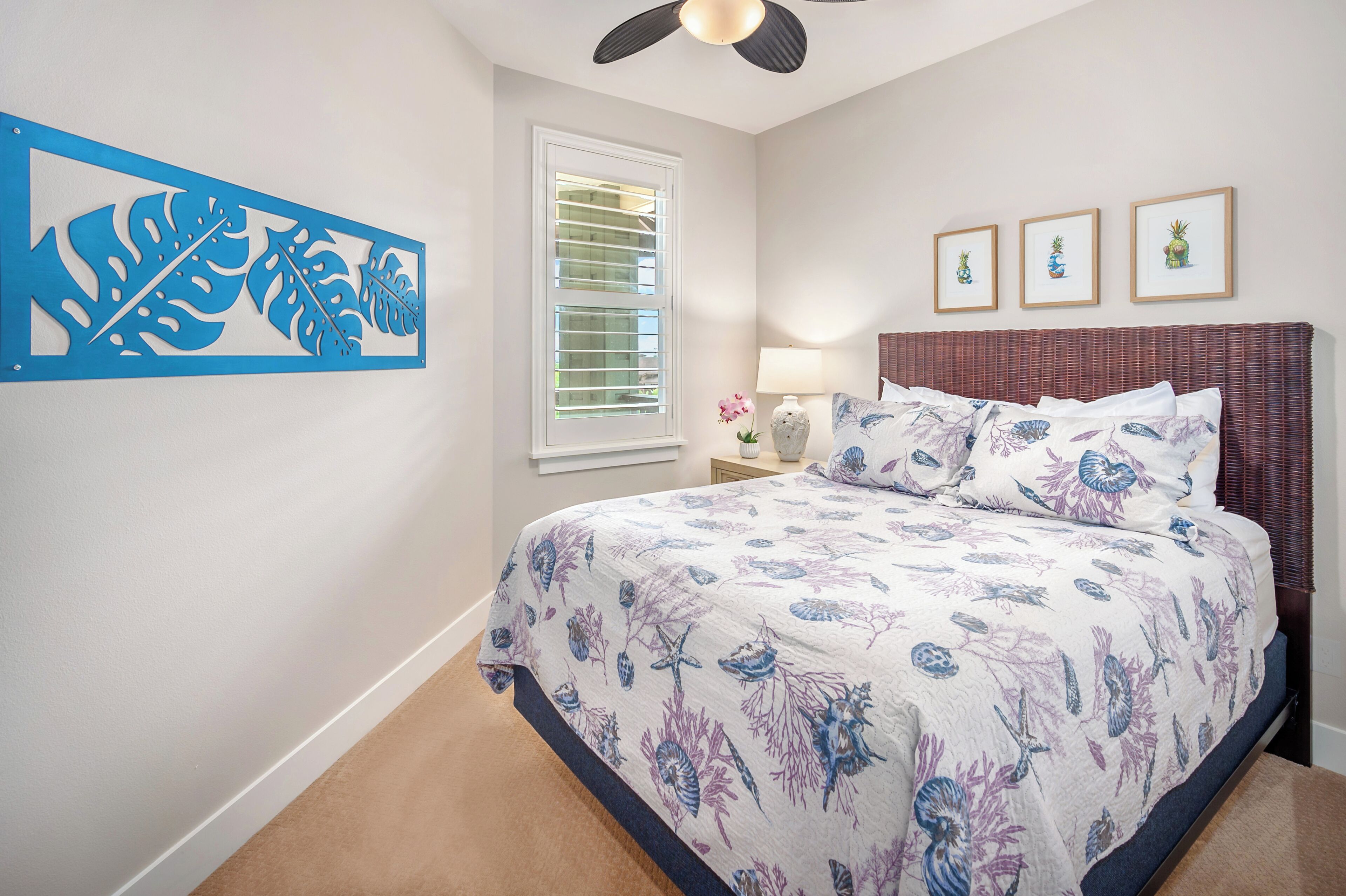 Une chambre à coucher avec un lit, un ventilateur de plafond, une fenêtre avec des stores et des œuvres d’art murales.