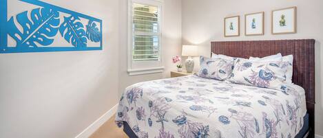 Un dormitorio con cama, ventilador de techo, ventana con persianas y decoración en la pared.