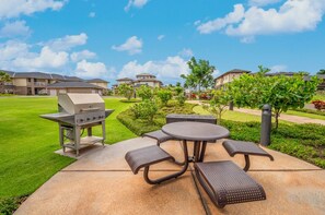 An outdoor patio with a grill, seating, and a well-maintained lawn.