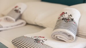 Toallas dobladas con diseños a rayas y bordados sobre una cama.