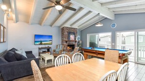 Una sala de estar acogedora con una mesa de billar, una chimenea y un amplio ventanal con vistas a una terraza.