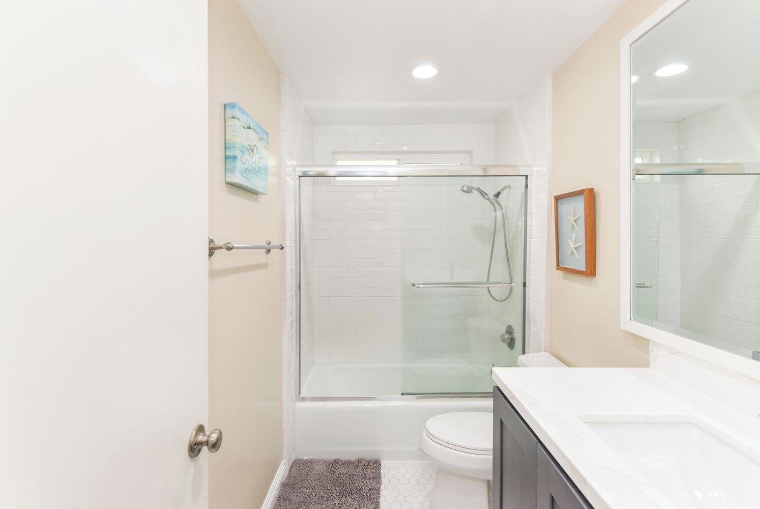 A modern bathroom with a glass-enclosed shower, a white toilet, and a vanity with a mirror.