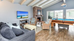 Una sala de estar con chimenea, mesa de billar y un ventanal con vistas a una terraza.