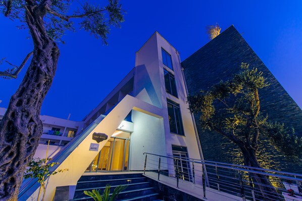 Un hôtel moderne doté d’une architecture originale, avec un escalier imposant et un grand arbre en premier plan.