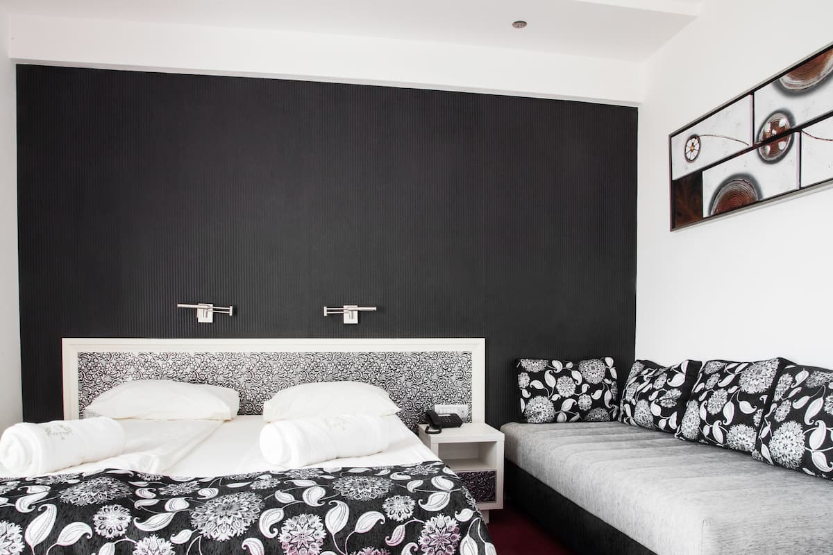 Ein modernes Hotelzimmer mit einem großen Bett, einer Couch und einem kleinen Nachttisch.