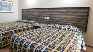 Une chambre d’hôtel avec deux lits, chacun recouvert d’une couvre-lit à motifs et agrémenté d’oreillers assortis. La tête de lit est faite de panneaux de bois foncé.
