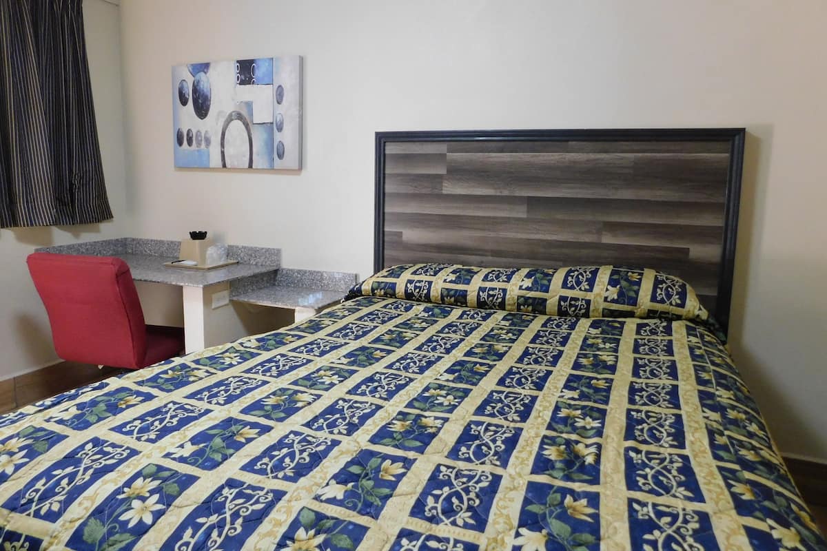 A hotel room with a bed, a desk, and a chair.