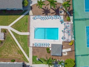 An aerial view of a swimming pool area with lounge chairs and a tennis court. - Stunning Gulf Front Three Bedroom Sanibel Condo (Sanibel)
