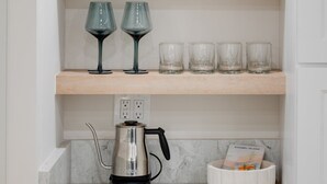 Una cocina con tres repisas de madera, una cafetera y un libro sobre la encimera.