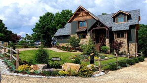 A lodge with a stone facade, wooden accents, and a landscaped front yard.