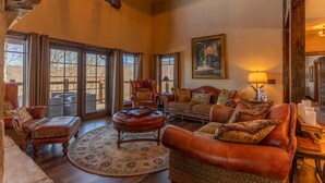 A spacious living room with leather furniture, large windows, and a cozy fireplace.