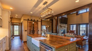 A spacious kitchen with a large island, wooden cabinets, and a stone fireplace.