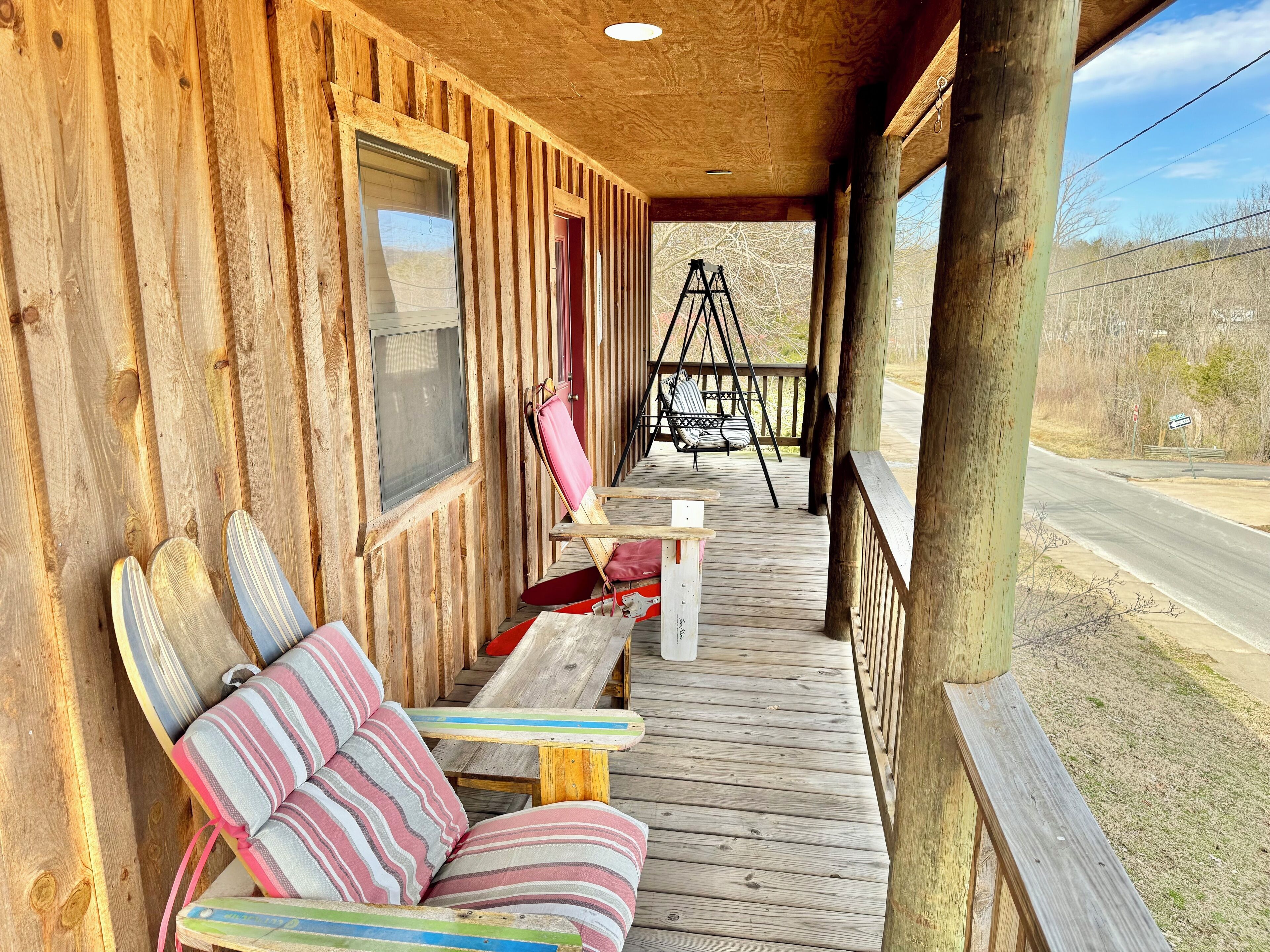Eine Holzveranda mit Schaukelstuhl, Bank und Tisch.