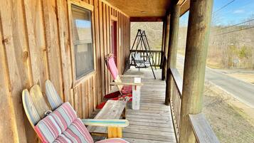 Eine Holzveranda mit Schaukelstuhl, Bank und Tisch.