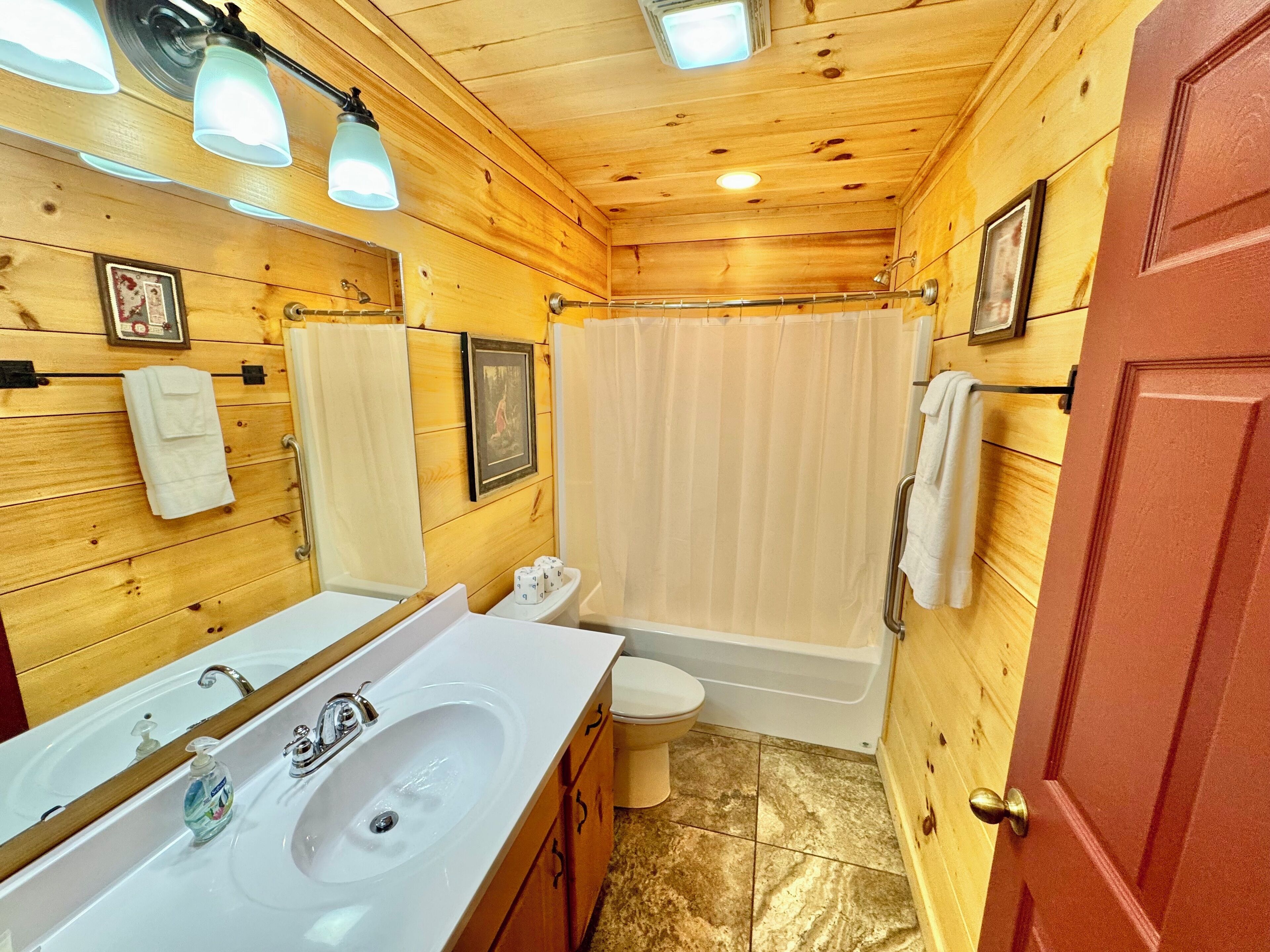 A wooden cabin bathroom with a sink, toilet, and bathtub.