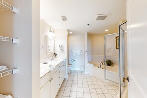 Features a large mirror, vanity, and separate shower area.