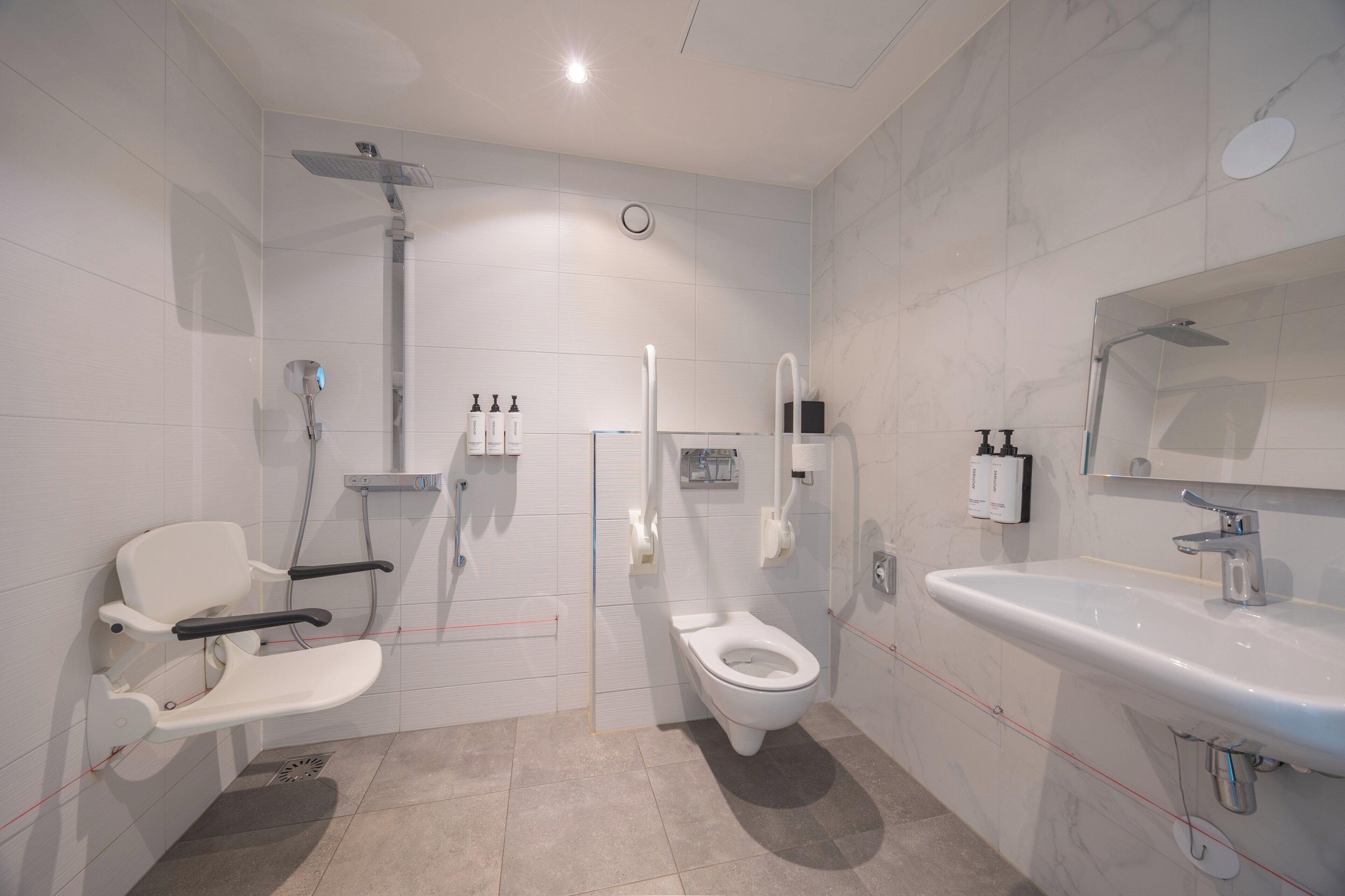A modern bathroom with a shower, toilet, and sink.